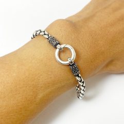 A detailed close-up of a handcrafted 925 sterling silver square box braided chain bracelet, featuring a prominent circular pendant clasp, worn on a wrist.