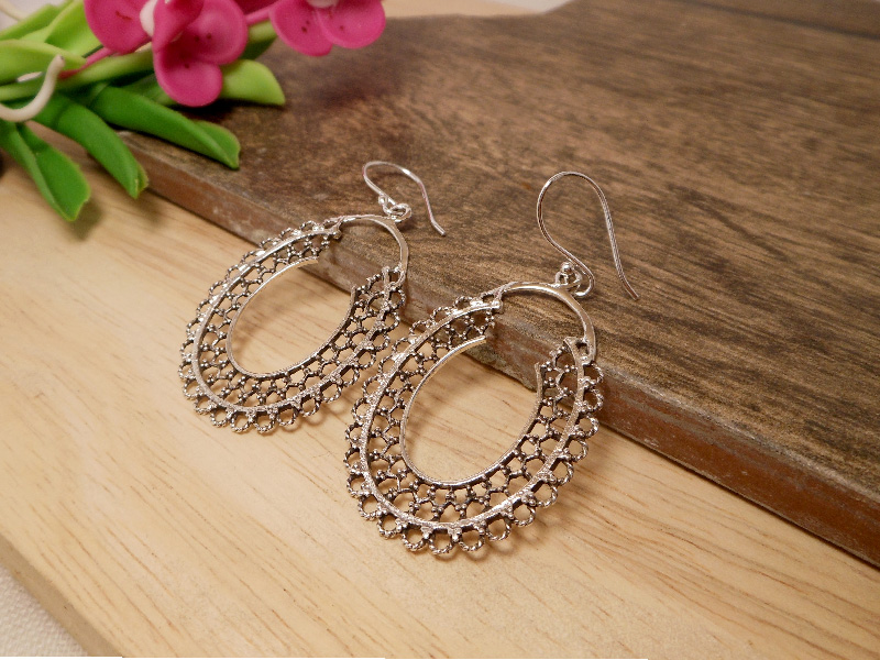 A pair of handcrafted 925 sterling silver mandala hoop drop earrings featuring intricate oval textured patterns, shown on a white display cup