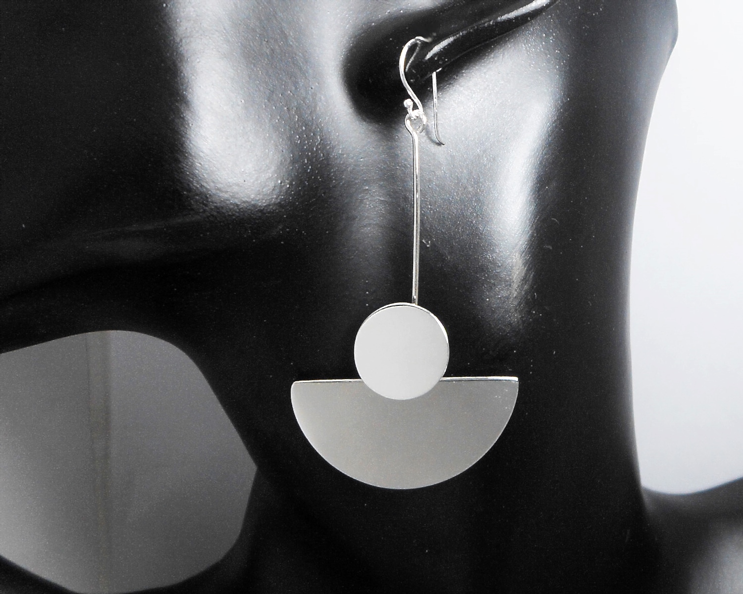 A pair of handcrafted 925 sterling silver dangle earrings featuring a modern geometric circle and semicircle drop design with a high-polished finish.