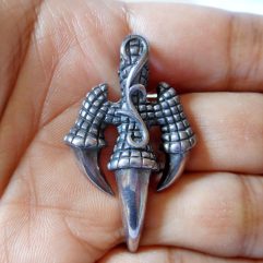 A detailed macro photograph of a handcrafted, oxidized 925 sterling silver eagle claw pendant resting on an open palm