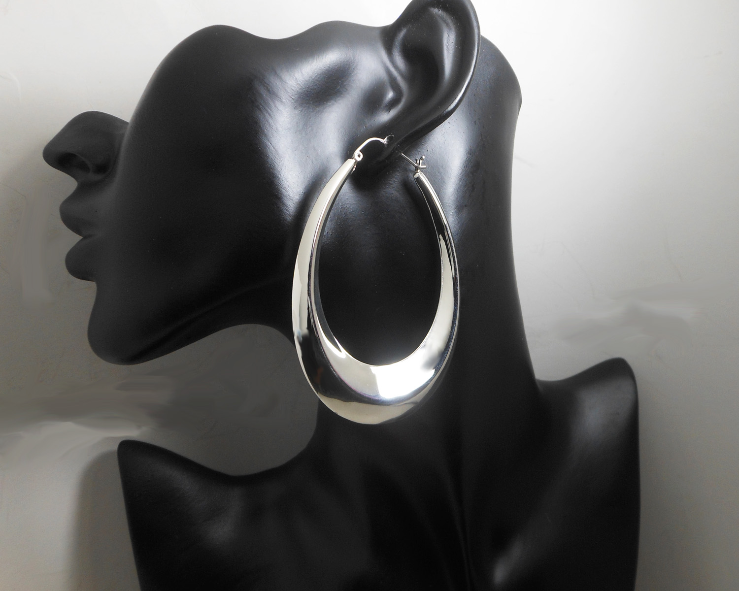 A pair of large, handcrafted 925 sterling silver tapered oval hoop earrings (75mm x 53mm), showcasing a bold, high-polished, puffy 3D design.