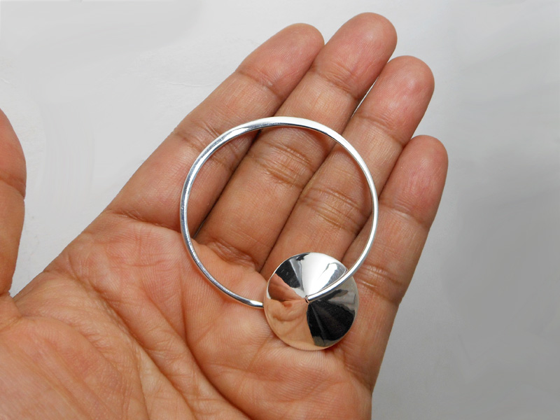 A pair of handcrafted 925 sterling silver drop stud earrings featuring a unique spinning Saturn-inspired planetary design, elegantly displayed on a hand.