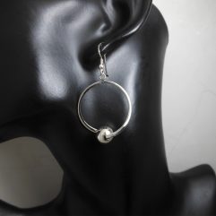 A pair of handcrafted 925 sterling silver drop earrings featuring a circular frame with a polished silver bead, displayed on a jewelry mannequin.