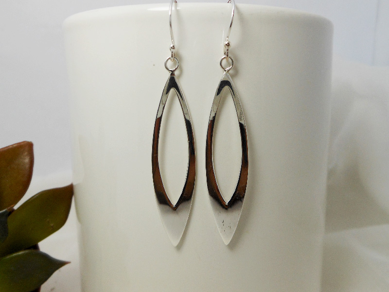 A pair of handcrafted 925 sterling silver open leaf drop earrings with a sleek, high-polished finish, shown on a white display stand.