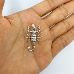 A detailed macro shot of a handcrafted 3D 925 sterling silver scorpion pendant with movable parts, displayed resting on an open palm.
