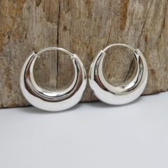 A pair of handcrafted 925 sterling silver puffy hoop earrings with a distinctive sculptural tribal-inspired shape, displayed against a rustic wooden background.