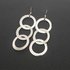 A pair of handcrafted 925 sterling silver drop earrings featuring three interconnected smooth, high-polished circles, displayed on a black background.