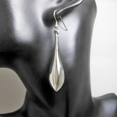 A pair of handcrafted 925 sterling silver elongated puffy teardrop earrings with a high-polished, reflective finish, displayed on a black mannequin.