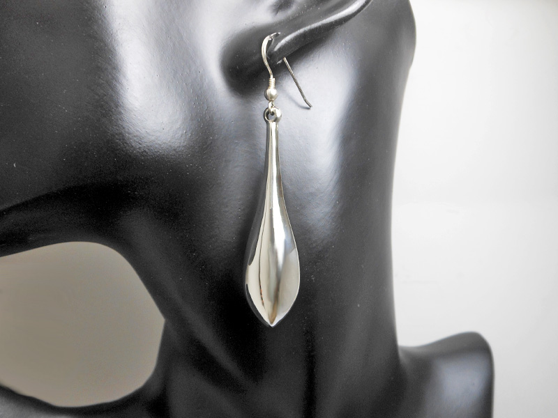 A pair of handcrafted 925 sterling silver elongated puffy teardrop earrings with a high-polished, reflective finish, displayed on a black mannequin.