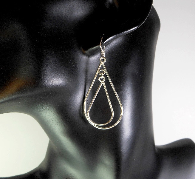 A pair of handcrafted 925 sterling silver double tapered oval hoop dangle earrings featuring a spinning, high-polished smooth finish on a black mannequin.