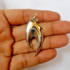 A macro shot of a sleek, high-polished 925 sterling silver fire flame pendant held in an open palm.