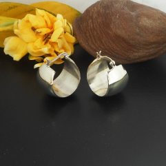 A pair of polished 925 sterling silver wide chubby hoop earrings featuring a secure latch back, displayed next to a decorative seed pod and flower.