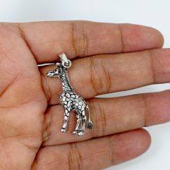 A detailed macro shot of a handcrafted, 3D 925 sterling silver giraffe pendant with movable parts, displayed resting on an open palm.