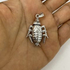 A close-up shot of a handcrafted 925 sterling silver bug pendant featuring movable parts, held in an open palm