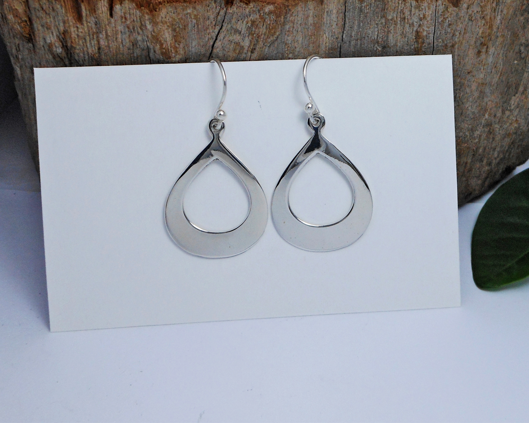 A pair of handcrafted 925 sterling silver elongated oval drop earrings featuring a sleek, high-polished finish, displayed on a white surface.