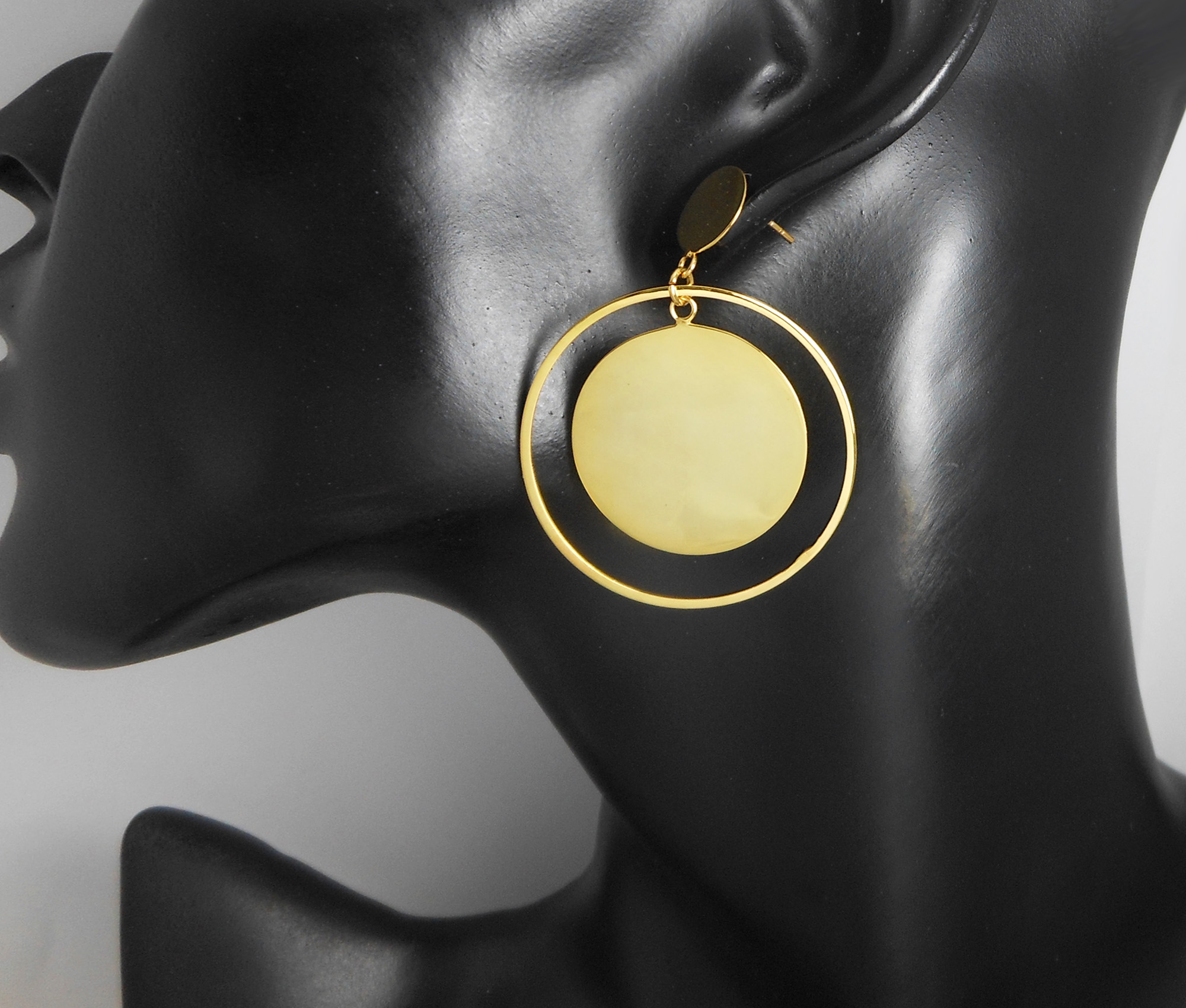 A pair of handcrafted 925 sterling silver drop earrings featuring a spinning inner round disc within an outer circle, displayed on a mannequin ear.