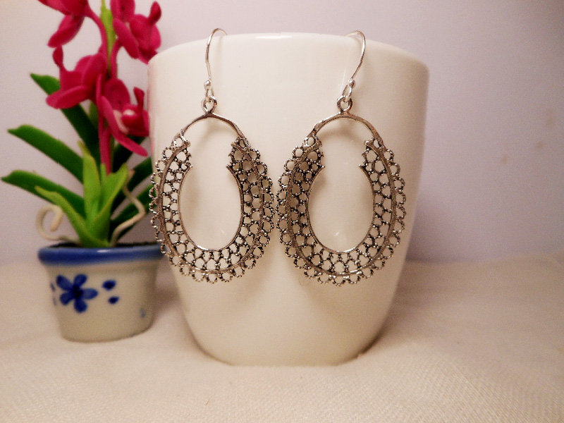 A pair of handcrafted 925 sterling silver mandala hoop drop earrings featuring intricate oval textured patterns, shown on a white display cup.