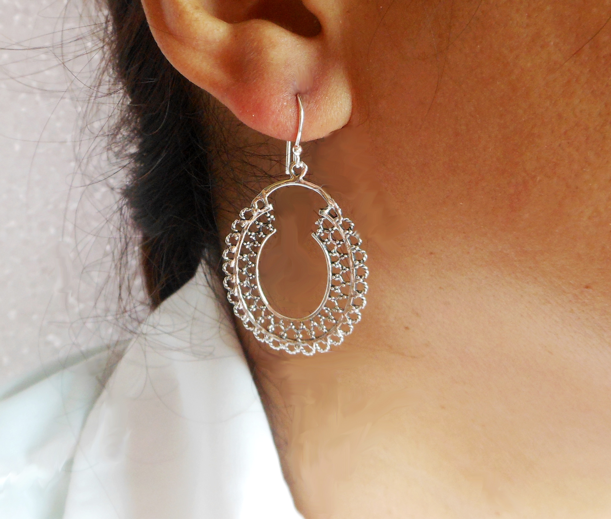 A pair of handcrafted 925 sterling silver mandala hoop drop earrings featuring intricate oval textured patterns, worn on a person's ear.