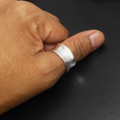 A handcrafted wide curved 925 sterling silver band ring shown on a hand
