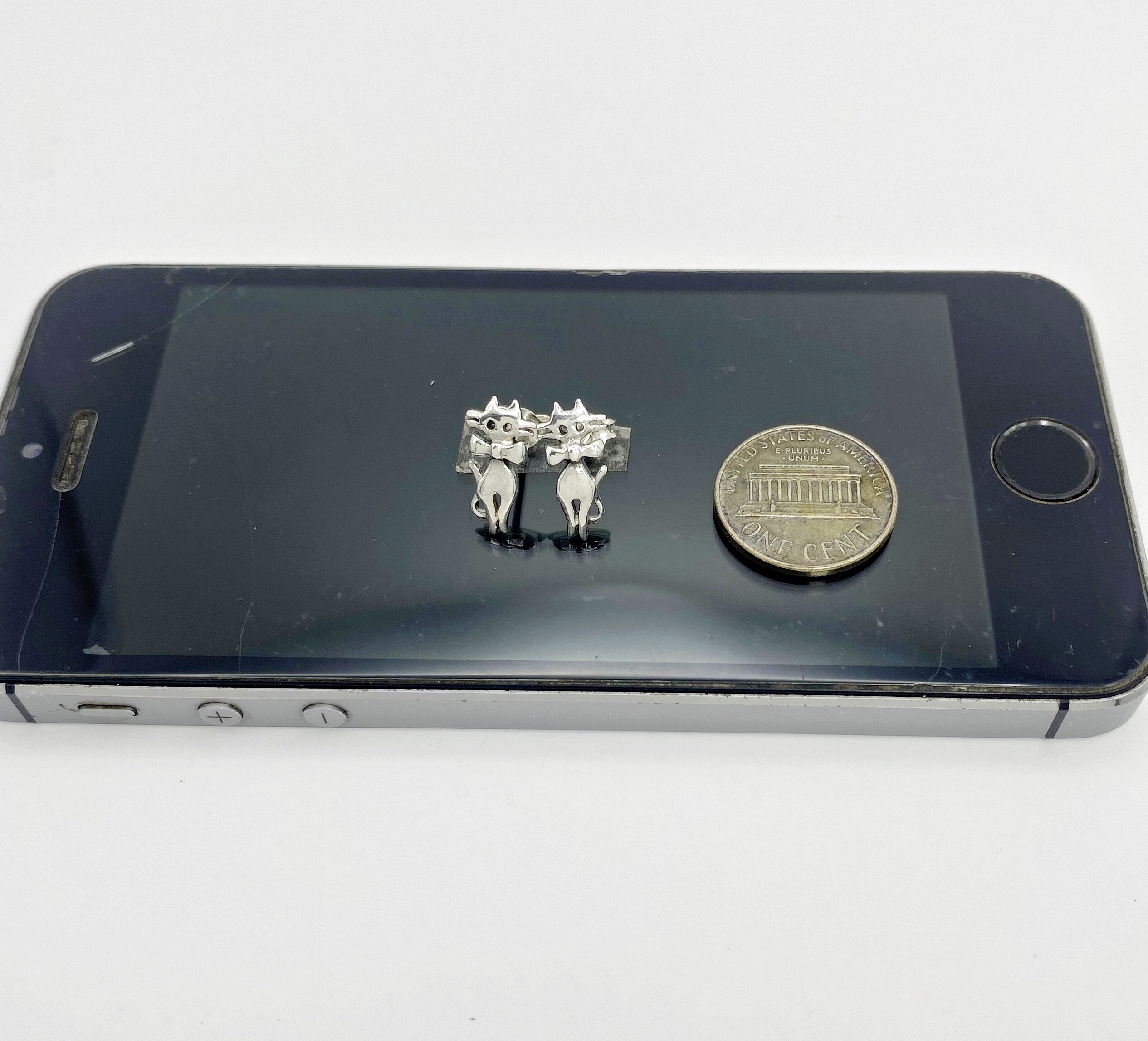 925 sterling silver cat earrings next to a coin for size comparison.