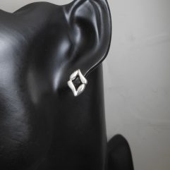 Pair of handmade 925 sterling silver stud earrings with an abstract evil eye shape on black mannequin