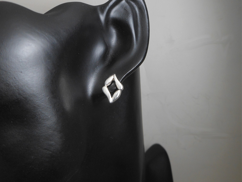 Pair of handmade 925 sterling silver stud earrings with an abstract evil eye shape on black mannequin