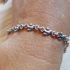 A close-up shot of a handcrafted 925 sterling silver bracelet featuring a repeating footprint link design, shown on a wrist.