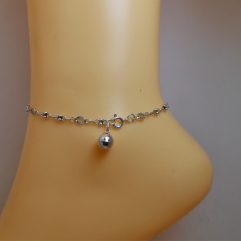 Detailed view of flower chain anklet with bell charm on model.