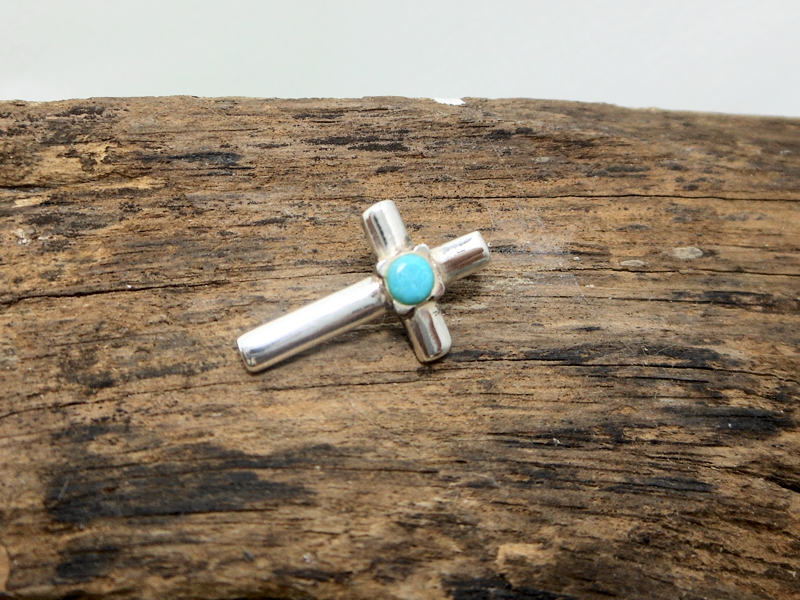 Detailed view of small sterling silver turquoise cross charm
