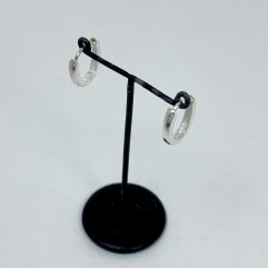 A pair of polished 925 sterling silver oval huggie hoop earrings, 2mm wide, displayed on a small black stand.