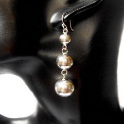 A pair of handcrafted 925 sterling silver triple ball dangle earrings with a tapered, high-polished design worn on a mannequin ear.