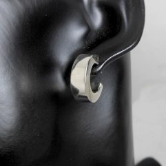 A pair of polished 925 sterling silver puffy open round hoop stud earrings worn on a black display mannequin ear.