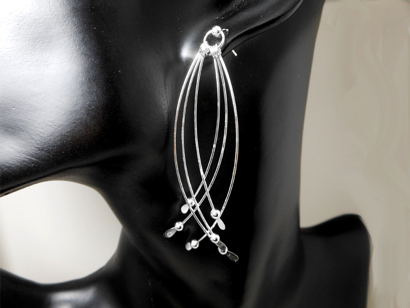 A pair of handcrafted 925 sterling silver multi-bar long dangle earrings, featuring several curved, slender silver bars ending in small bead and leaf tips, worn on a black mannequin ear.