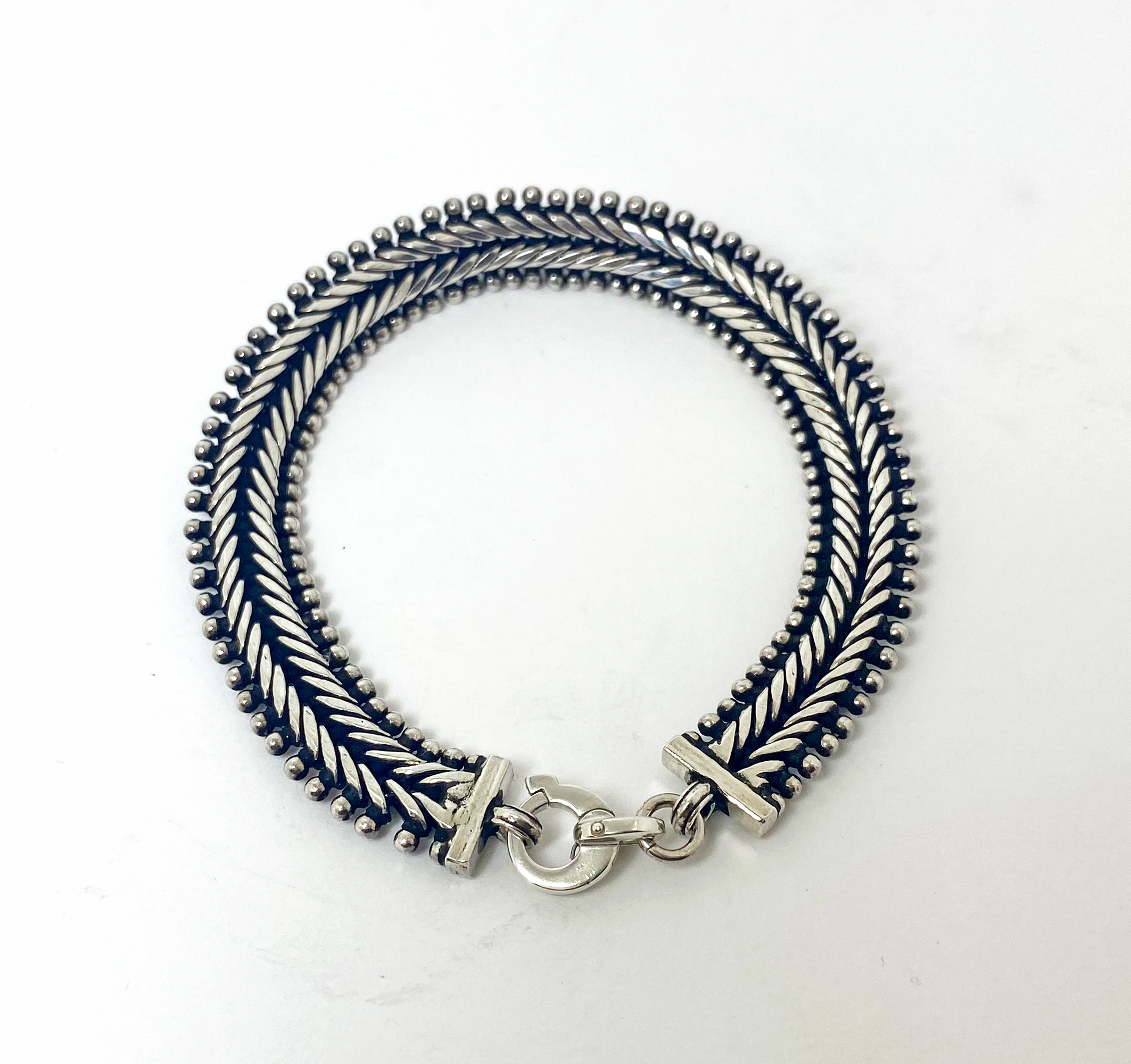 A detailed view of a thick, handcrafted 925 sterling silver centipede link chain bracelet featuring intricate, high-polished, and oxidized segments, secured with a sturdy clasp.