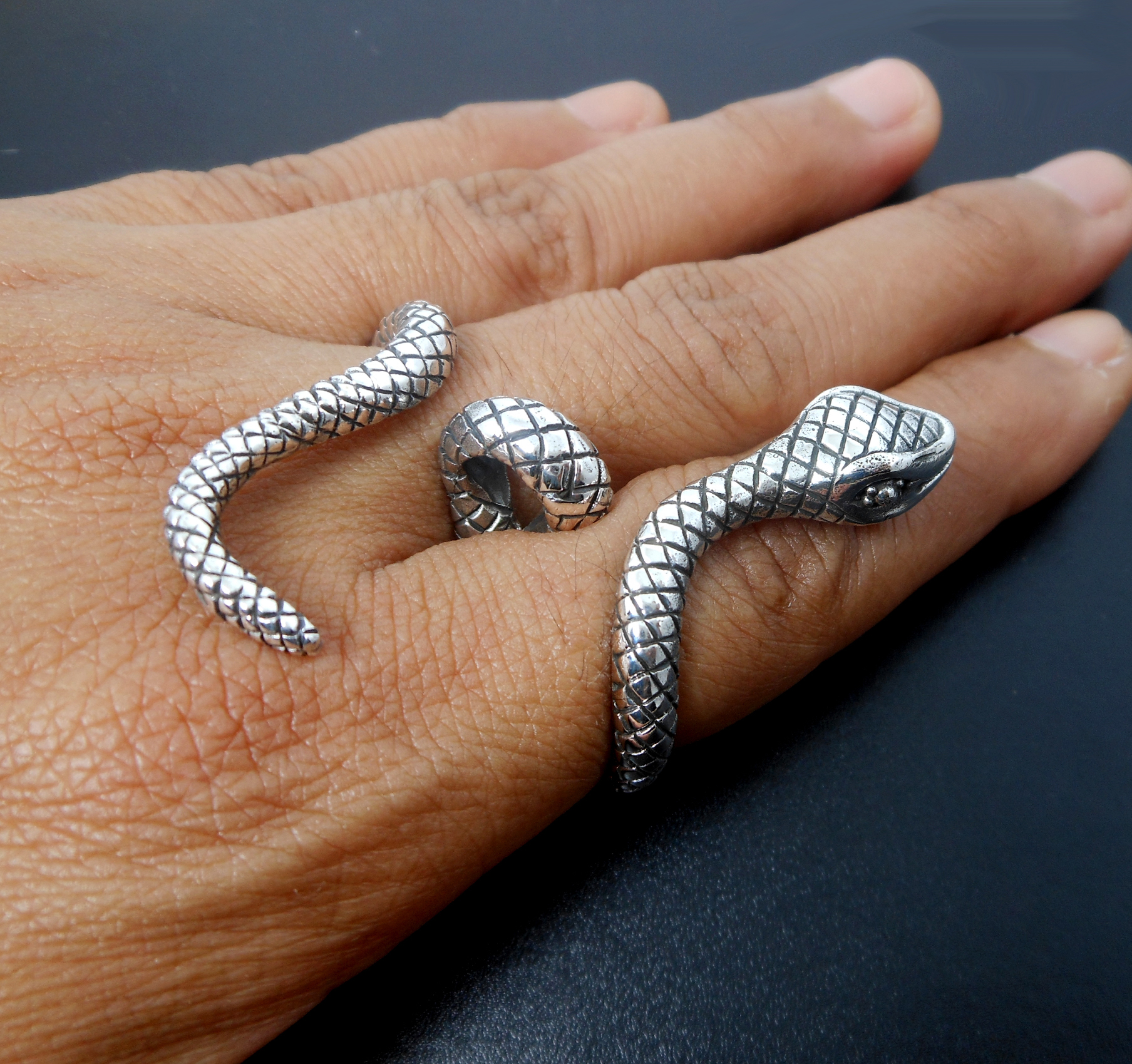 A handcrafted 925 sterling silver snake-shaped wrap ring with intricate texture, shown worn on a finger