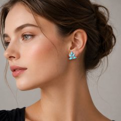 European model wearing turquoise and coral floral dangle earrings (ET78) with a black top on a light gray studio background.