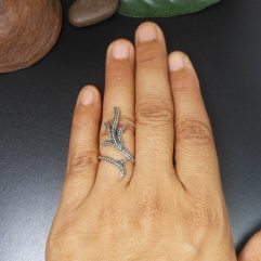 A handcrafted 925 sterling silver ring featuring a detailed, textured leafy branch design in an adjustable wrap-around style, shown on a hand