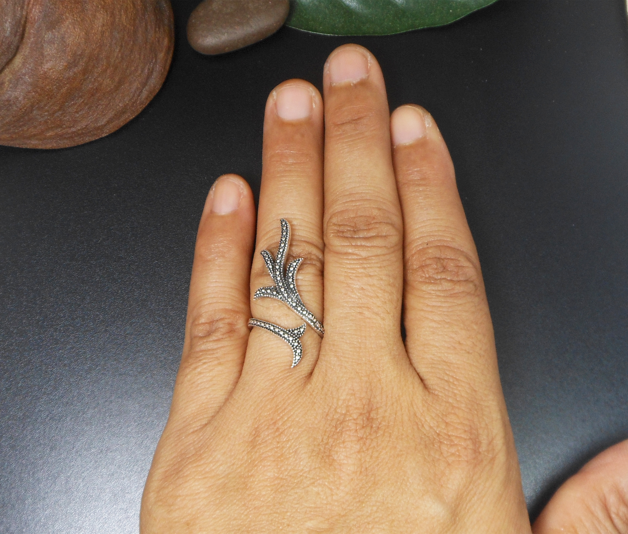 A handcrafted 925 sterling silver ring featuring a detailed, textured leafy branch design in an adjustable wrap-around style, shown on a hand