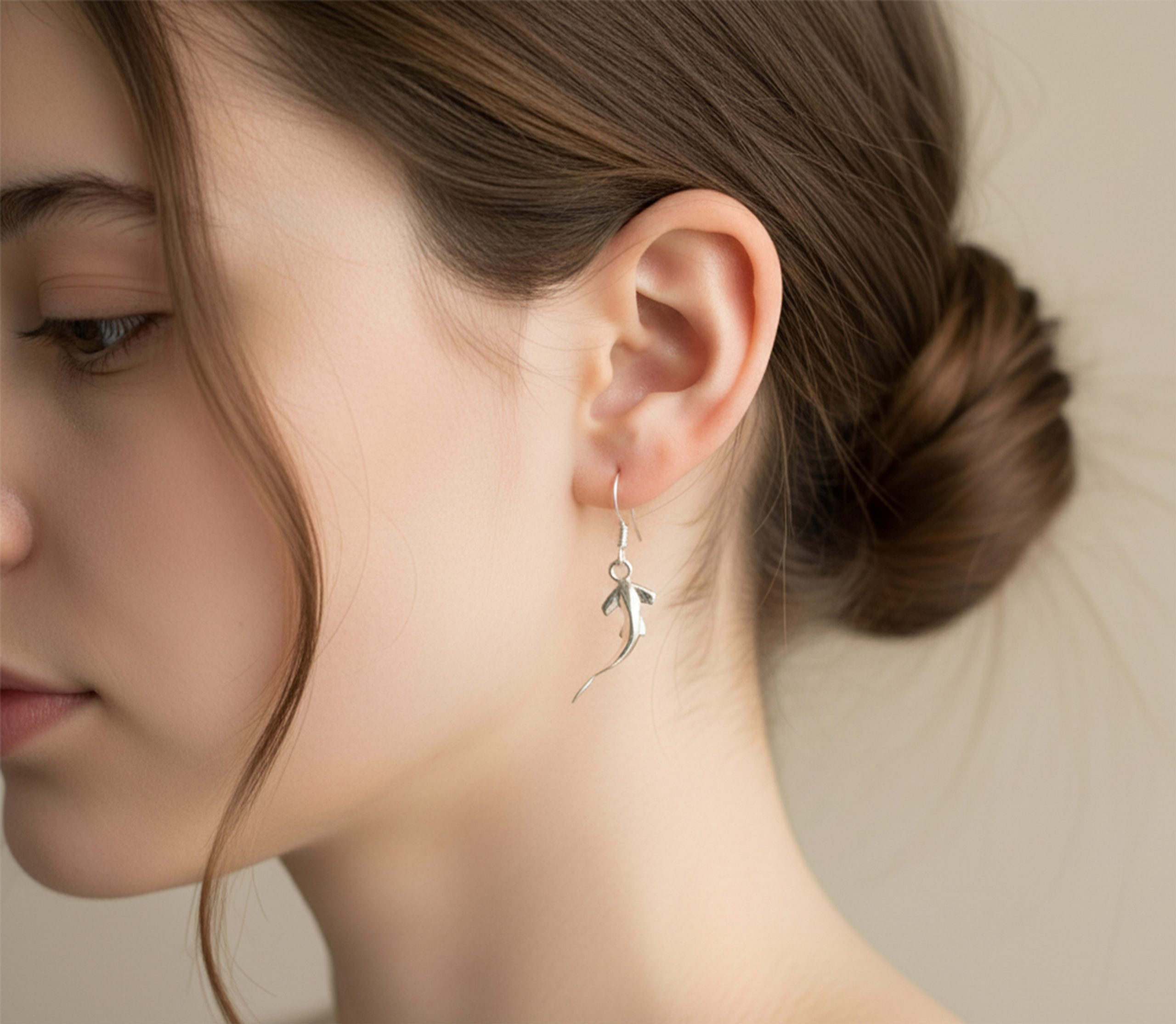 Side profile of a woman wearing sterling silver hammerhead shark earrings