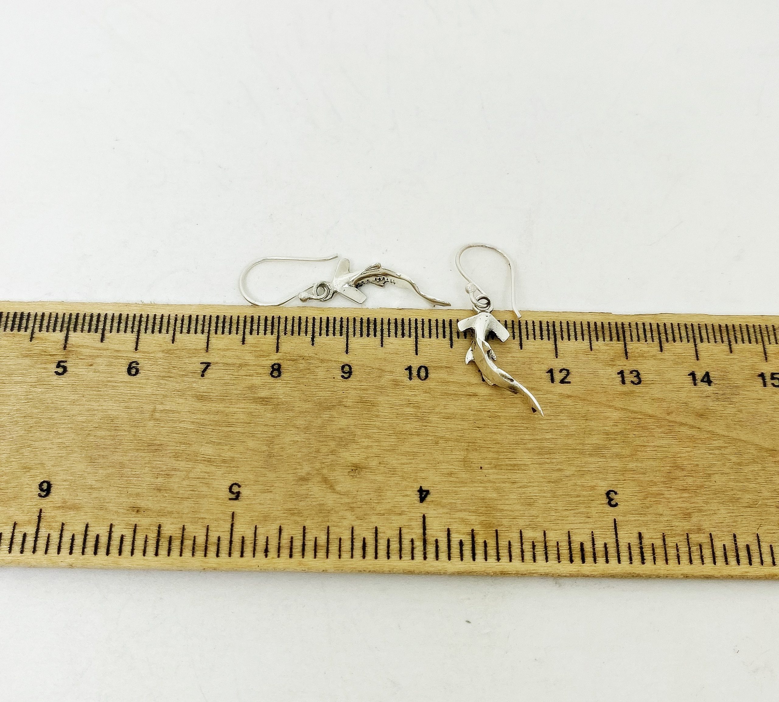 Measuring the size of hammerhead shark earrings with a ruler