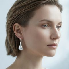 Side profile of a woman with short hair wearing polished sterling silver puffy teardrop earrings.