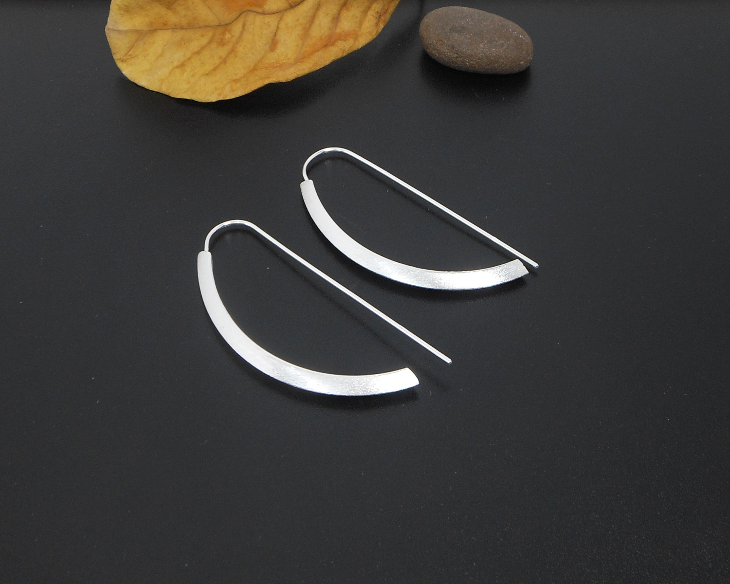 Pair of minimalist silver arc D-hoop threader earrings.