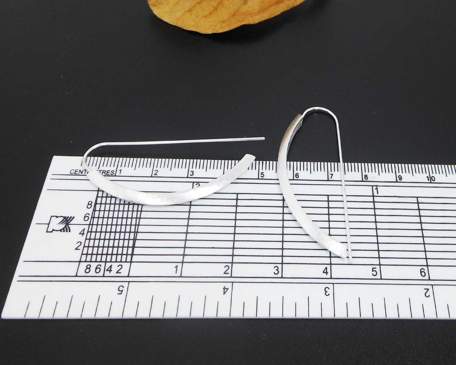 Sterling silver arc D-hoop threader earrings shown with a measuring tool for size reference.