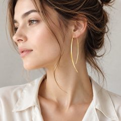 A model wearing long, gold-plated arc threader dangle earrings.