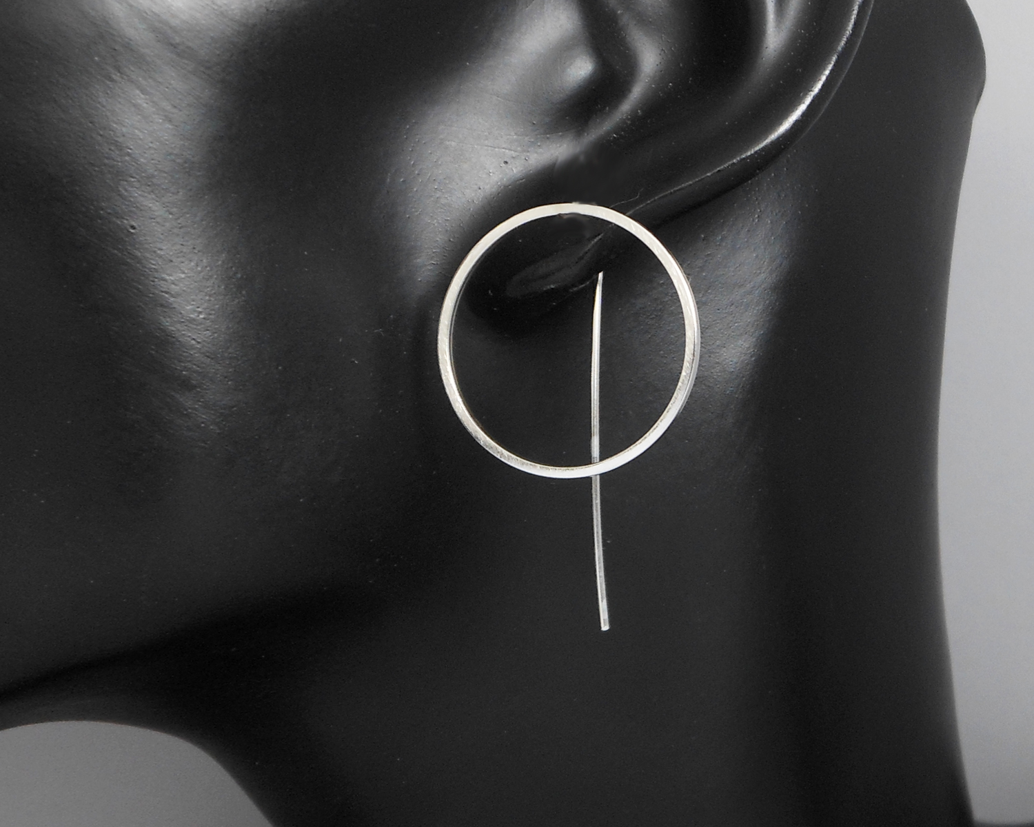 circle threader earrings displayed on a black mannequin bust.