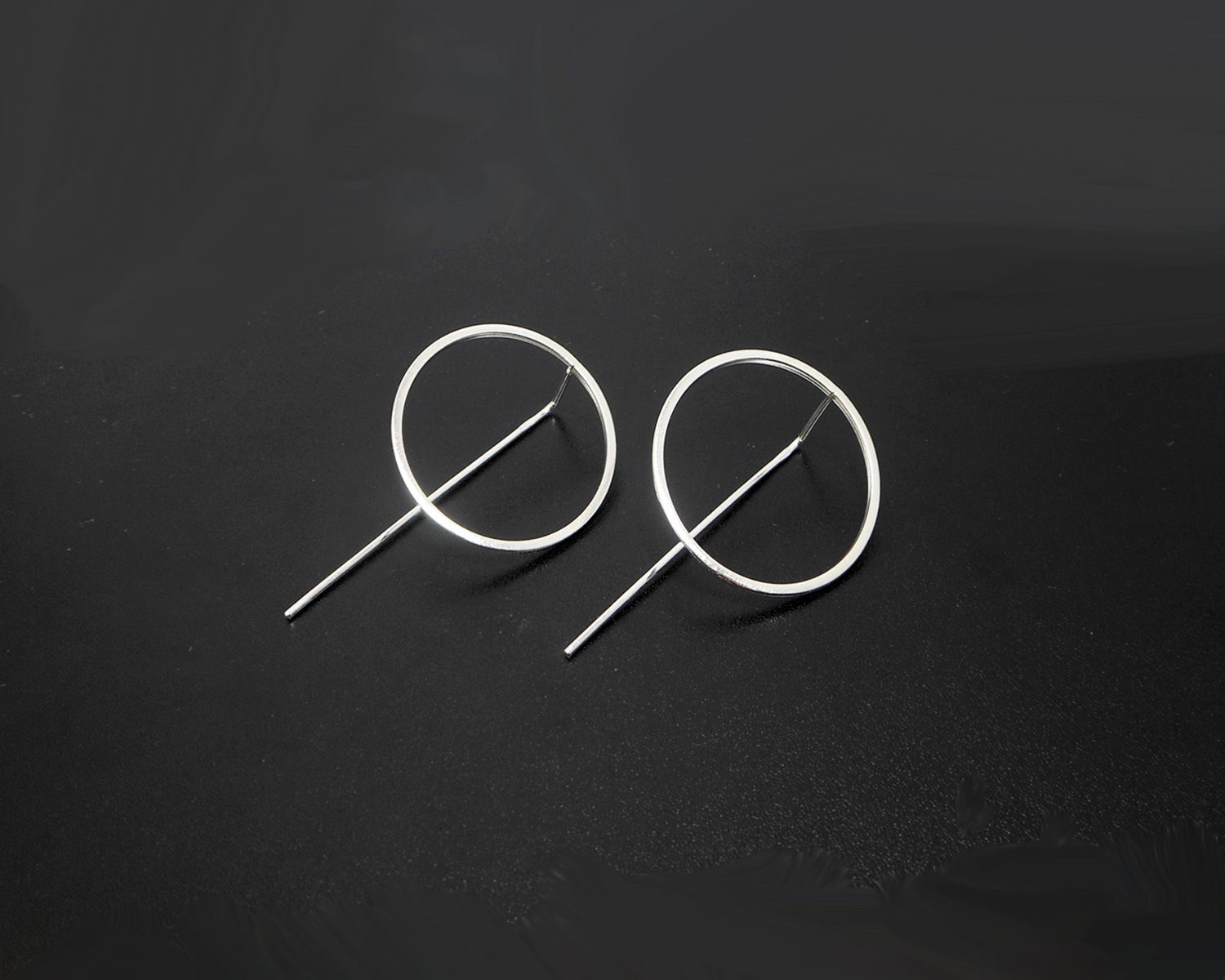 Pair of circle threader earrings on a dark surface.