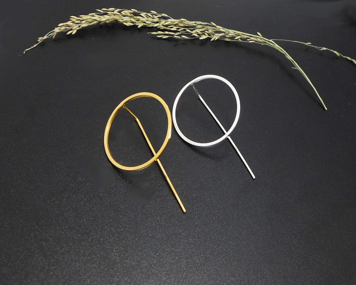 Gold and silver circle threader earrings on a dark surface.
