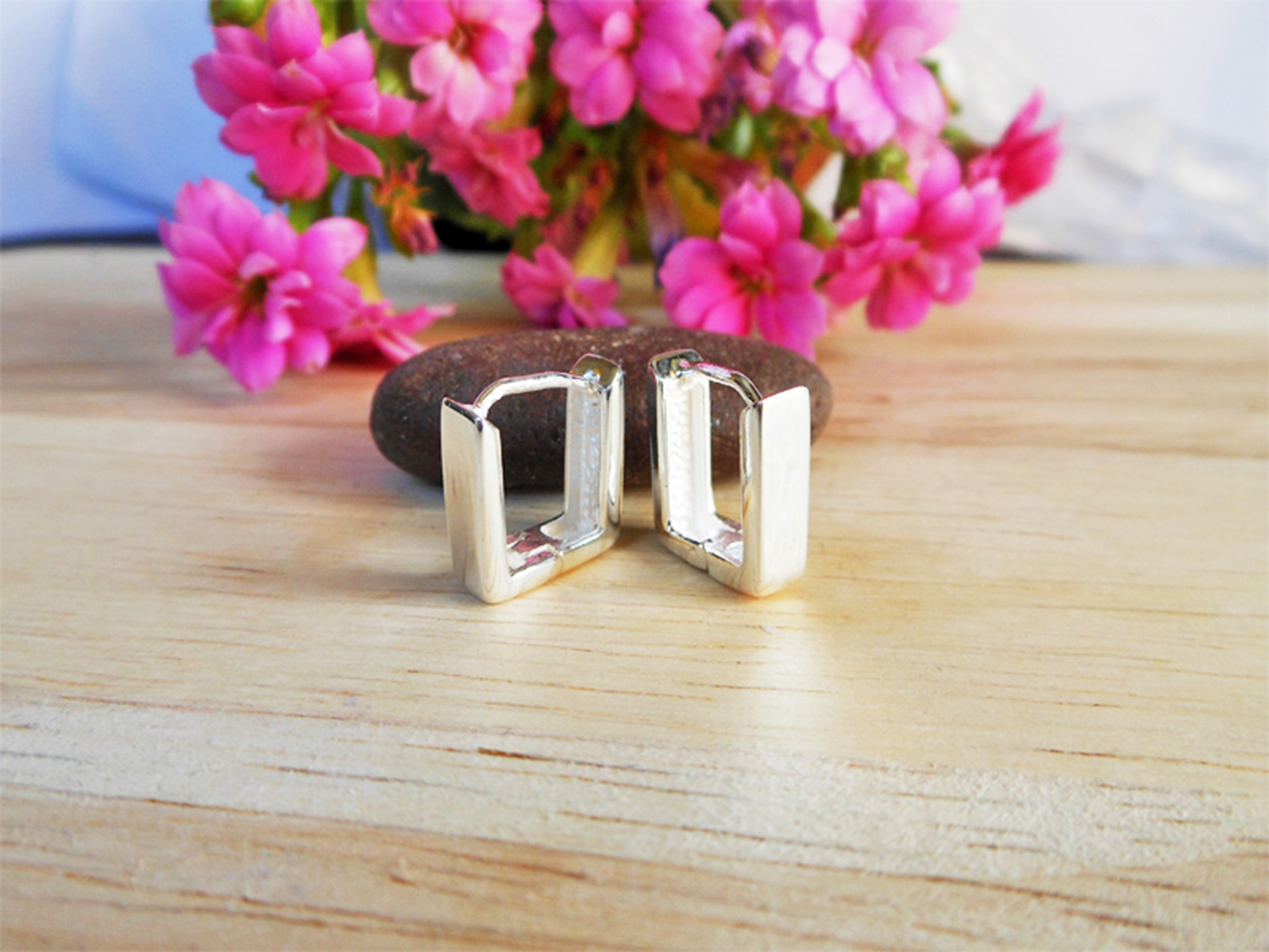 A pair of handmade 925 sterling silver flat square huggie earrings displayed against a floral background.