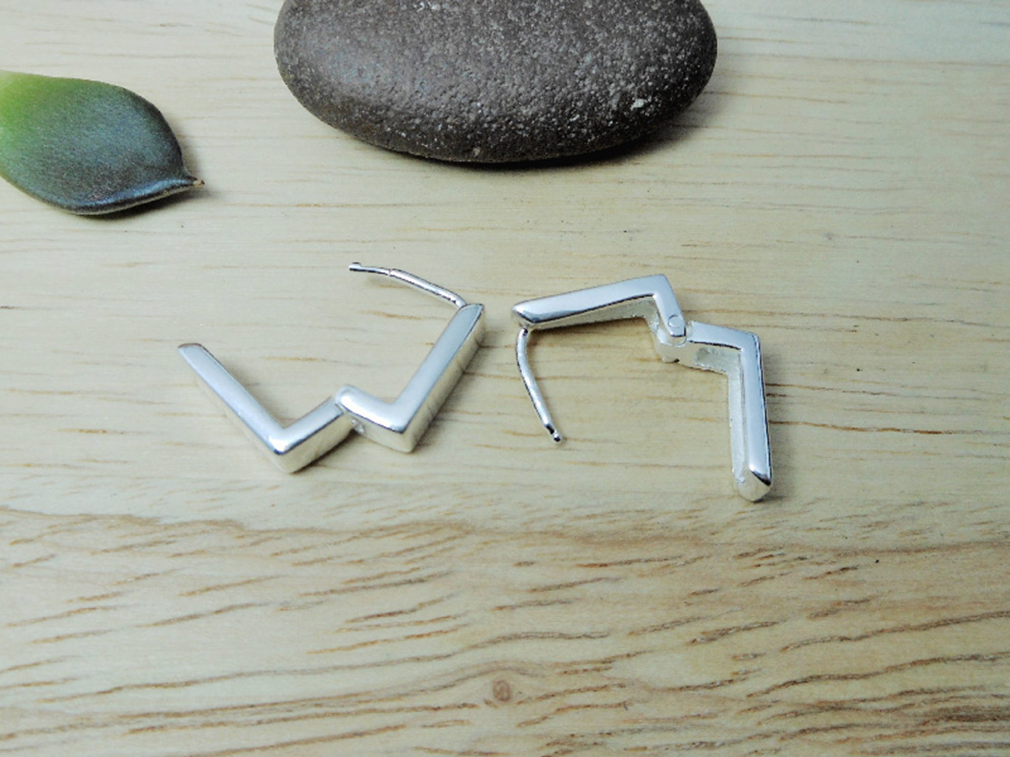 A close-up of handmade 925 sterling silver flat square huggie earrings.