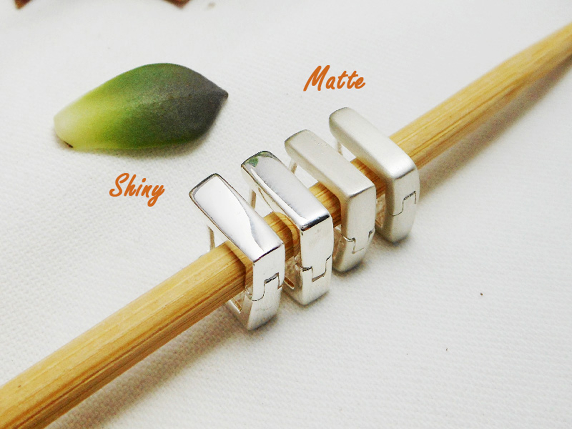 Handmade 925 sterling silver flat square huggie earrings arranged on a wooden prop.